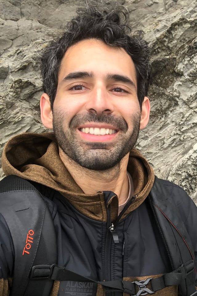 Portrait of Manuel Posso outside in front of a rockwall